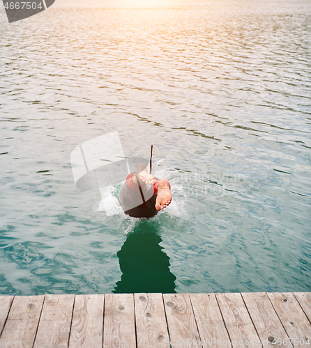 Image of triathlon athlete jumping in water and starting with training