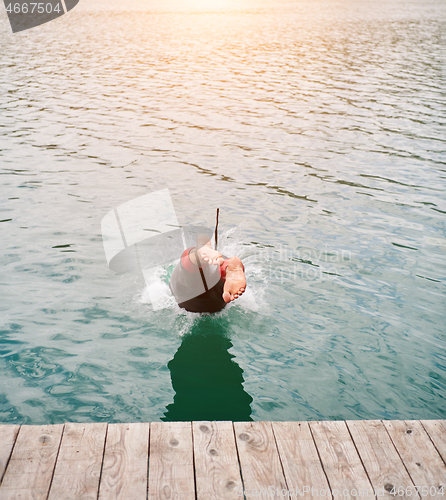 Image of triathlon athlete jumping in water and starting with training