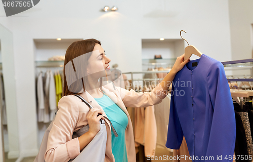 Image of happy woman choosing clothes at clothing store