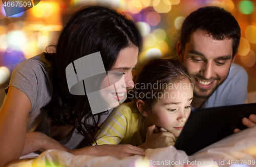 Image of family with tablet pc in bed at night at home