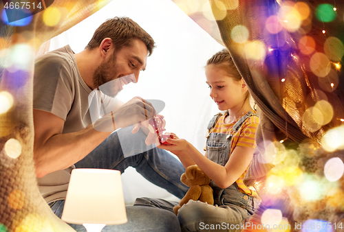 Image of family playing tea party in kids tent at home