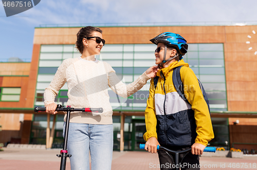 Image of mother and son in helmet with schooter near school