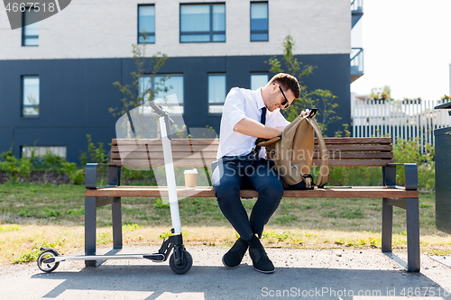 Image of businessman with bag, scooter and coffee in city