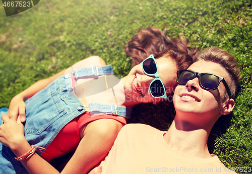 Image of happy teenage couple lying on grass at summer