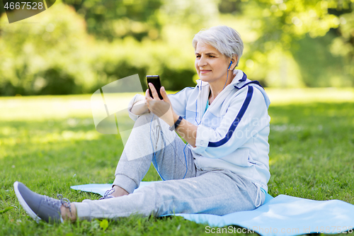 Image of sporty senior woman with earphones and smartphone