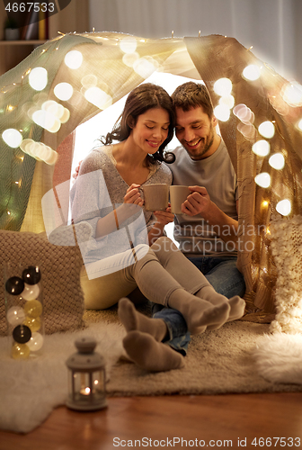 Image of couple drinking coffee or tea in kids tent at home