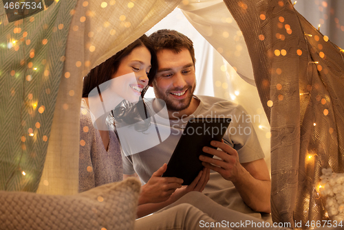 Image of happy couple with tablet pc in kids tent at home