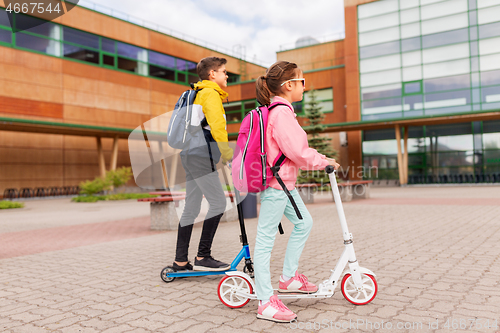 Image of school children with backpacks riding scooters