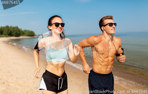 Image of couple with phones and arm bands running on beach