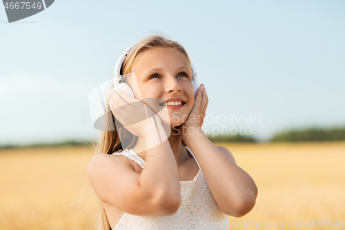 Image of happy girl in headphones on cereal field in summer