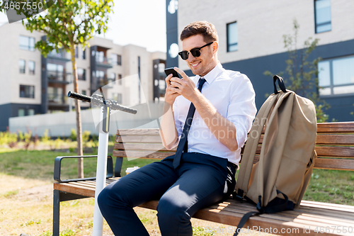 Image of businessman with smartphone, backpack and scooter