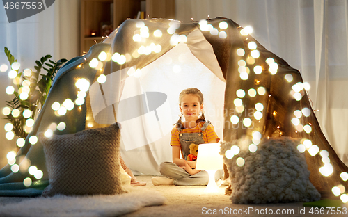 Image of little girl with toys in kids tent at home