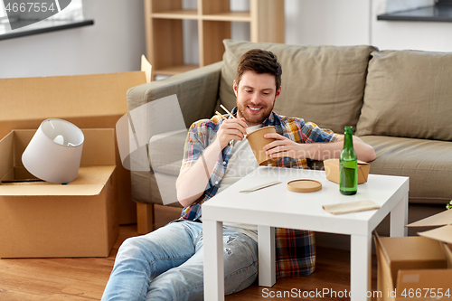 Image of smiling man eating takeaway food at new home