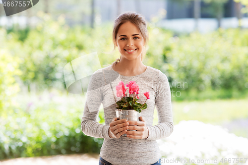 Image of young woman with cyclamen flowers at summer garden