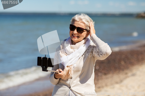 Image of senior woman taking selfie on beach