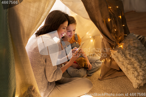 Image of happy family with smartphone in kids tent at home