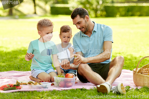 Image of family with smartphone having picnic at park