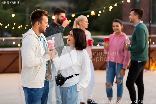 Image of friends with drinks in party cups at rooftop