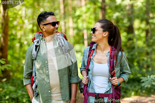 Image of mixed race couple with backpacks hiking in forest