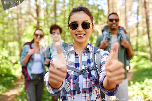 Image of friends with backpacks showing thumbs up in forest