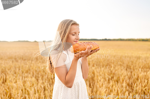 Image of girl smelling loaf of white bread on cereal field