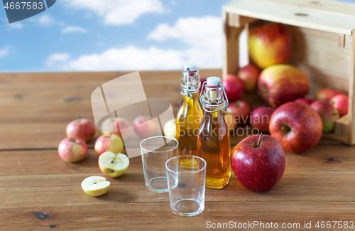 Image of glasses and bottles of apple juice on wooden table