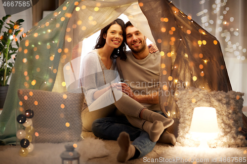 Image of happy couple in kids tent at home