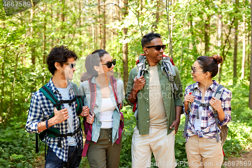 Image of friends with backpacks on hike talking in forest