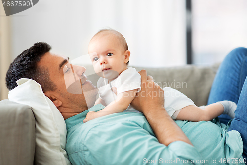 Image of middle aged father with baby lying on sofa at home