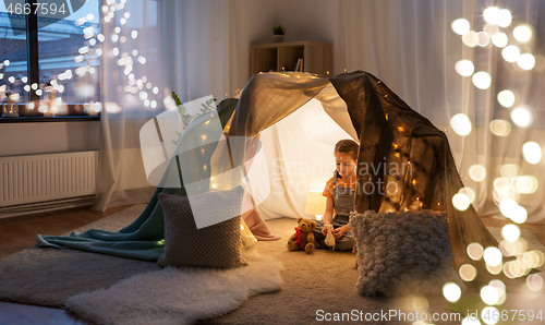 Image of little girl with toys in kids tent at home