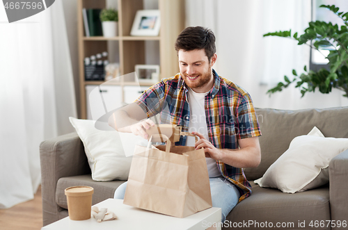 Image of smiling man unpacking takeaway food at home