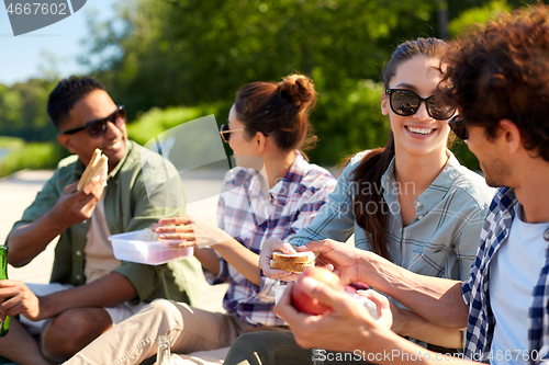 Image of happy friends having picnic on lake pier in summer