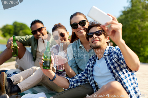 Image of friends with drinks taking selfie by smartphone