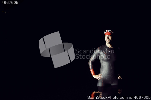 Image of authentic triathlete swimmer having a break during hard training on night