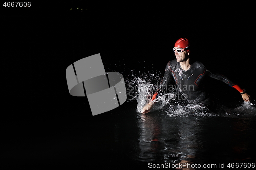 Image of triathlon athlete finishing swimming training at dark night