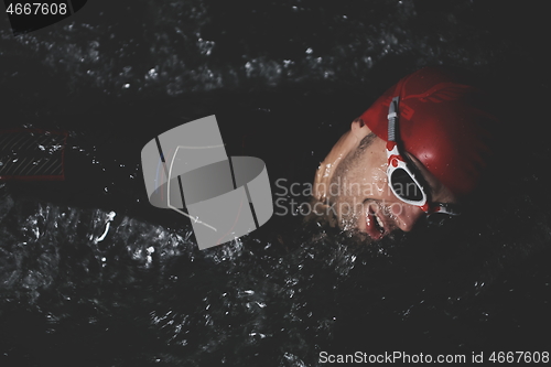 Image of triathlon athlete swimming in dark night wearing wetsuit