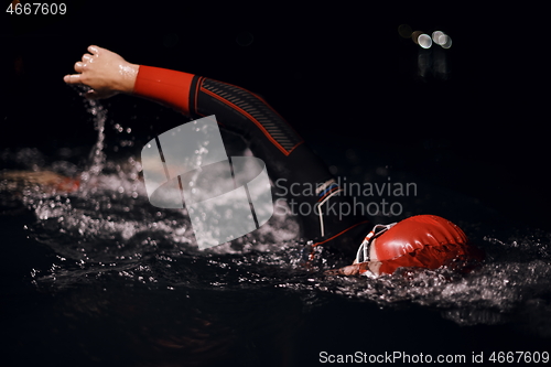 Image of triathlon athlete swimming in dark night wearing wetsuit