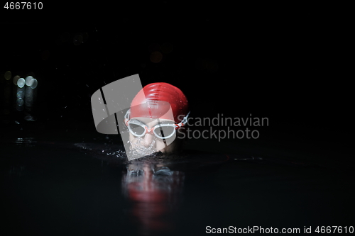 Image of authentic triathlete swimmer having a break during hard training on night