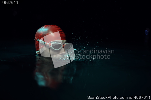 Image of authentic triathlete swimmer having a break during hard training on night neon gel light