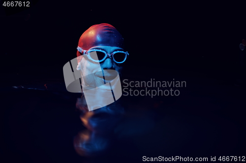 Image of authentic triathlete swimmer having a break during hard training on night neon gel light