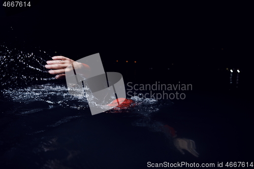 Image of triathlon athlete swimming in dark night wearing wetsuit
