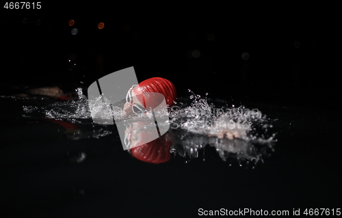 Image of triathlon athlete swimming in dark night wearing wetsuit