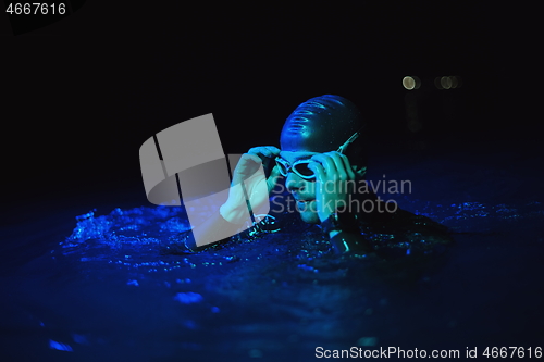 Image of authentic triathlete swimmer having a break during hard training on night neon gel light