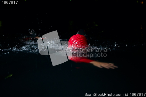 Image of triathlon athlete swimming in dark night wearing wetsuit