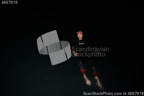 Image of triathlon athlete swimming in dark night wearing wetsuit