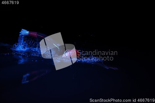 Image of real triathlon athlete swimming in dark night