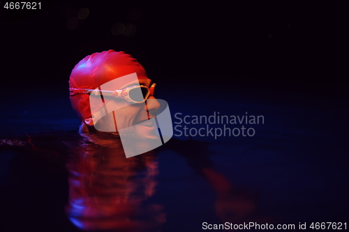 Image of authentic triathlete swimmer having a break during hard training on night neon gel light