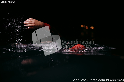 Image of triathlon athlete swimming in dark night wearing wetsuit