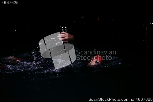 Image of triathlon athlete swimming in dark night wearing wetsuit