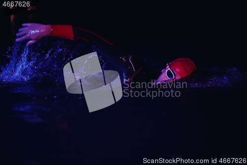 Image of real triathlon athlete swimming in dark night